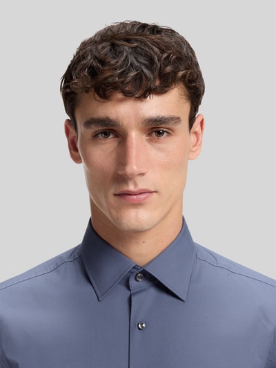 Männermodel trägt Slim Fit Businesshemd aus Baumwoll-Mix Modell 'H-HANK-KENT' von BOSS, Optik: Unifarben, Nahaufnahme Oberkörper.