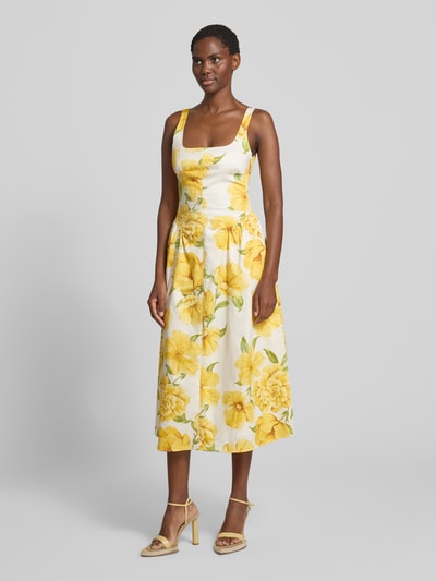 Frauenmodel trägt Midikleid im Allover-Look Modell 'ISLAND' von MANGO, gelbe Blumen auf weiß, Baumwoll-Elasthan-Mix, A-Linie, Karree-Ausschnitt, Ganzkörperansicht von vorne.