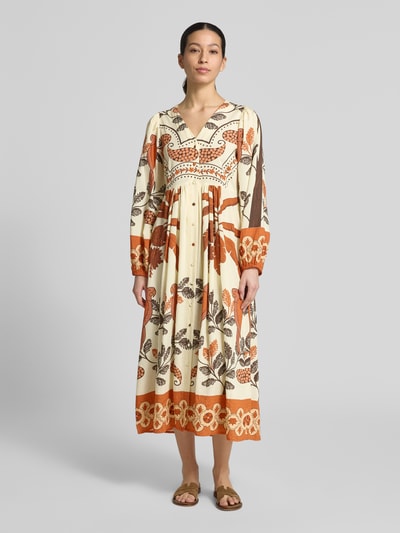 Frauenmodel trägt Midikleid aus Viskose-Mix mit V-Ausschnitt Modell 'Sarai' von LOLLYS LAUNDRY im Allover-Look, A-Linie, lange Ärmel, Knopfleiste, cremefarbene Basis mit orangen und braunen floralen Elementen, Rückenlänge bei Größe S 125 cm, Brustweite 46 cm, Ärmellänge 63 cm, Ganzkörperansicht von vorne.