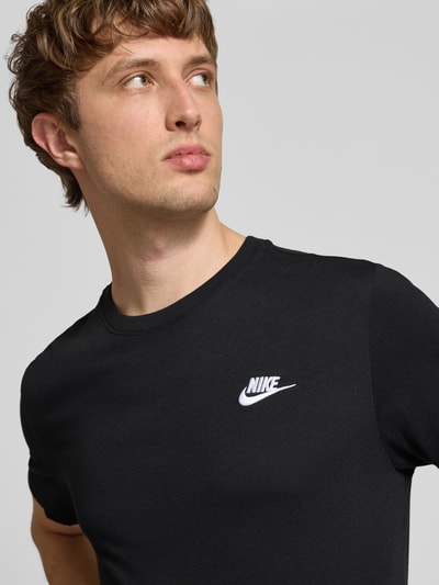 Männermodel trägt T-Shirt mit Label-Stitching von Nike in Schwarz, Reine Baumwolle, Regular-Fit, Rundhalsausschnitt, Nahaufnahme Oberkörper.