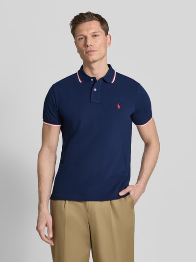 Männermodel trägt Slim Fit Poloshirt aus reiner Baumwolle von Polo Ralph Lauren in Optik: Unifarben mit Logo-Stitching, Ganzkörperansicht von vorne.