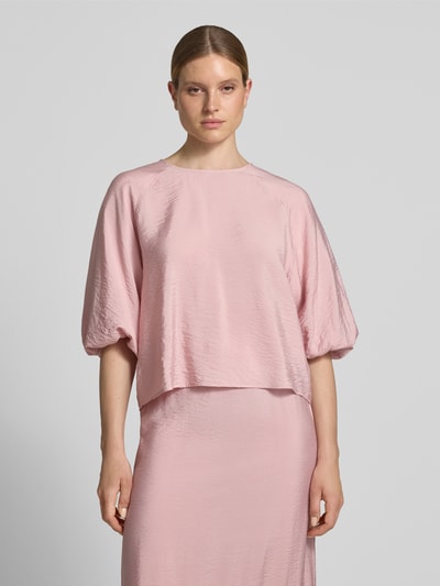 Frauenmodel trägt Regular Fit Bluse aus Viskose-Mix mit 3/4-Arm von Christian Berg Woman in Hellrosa, leicht glänzende Textur, Rundhalsausschnitt, Ganzkörperansicht von vorne.