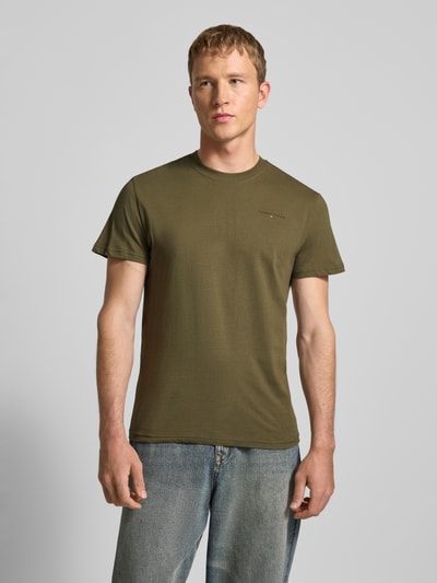 Männermodel trägt Slim Fit T-Shirt aus reiner Baumwolle von Tommy Jeans in Optik: unifarben mit Label-Print, Rundhals, Kurzarm, Ganzkörperansicht von vorne.