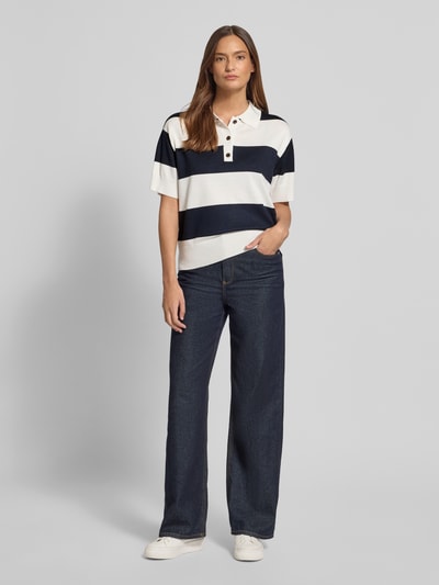 Frauenmodel trägt Regular Fit Poloshirt aus Viskose-Mix Modell 'LULS' von ICHI, gestrickte Optik, breite Querstreifen, Ganzkörperansicht von vorne.