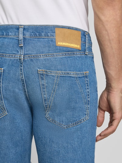 Männermodel trägt Slim Fit Jeansshorts aus Baumwoll-Mix Modell 'NAAILO' von Armedangels in Denim-Optik mit Label-Patch, Detailaufnahme Rückansicht.