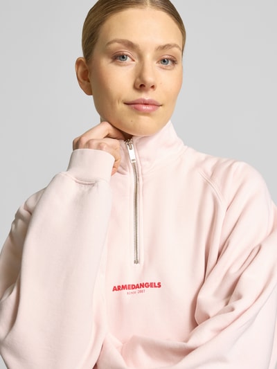 Frauenmodel trägt Oversized Sweatshirt aus reiner Baumwolle von Armedangels, Optik: Unifarben, Passform: Oversized, Label-Print, Troyer, Langarm, Raglanärmel, Materialverarbeitung: Sweat, Material: Reine Baumwolle, Nahaufnahme Oberkörper.