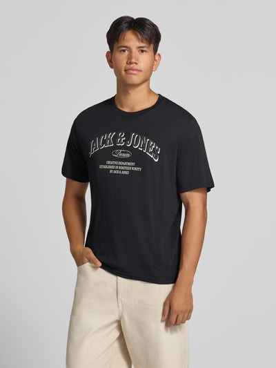 Männermodel trägt schwarzes Regular Fit T-Shirt aus reiner Baumwolle Modell 'Denver' von JACK & JONES mit Logo-Print, Nahaufnahme Oberkörper.
