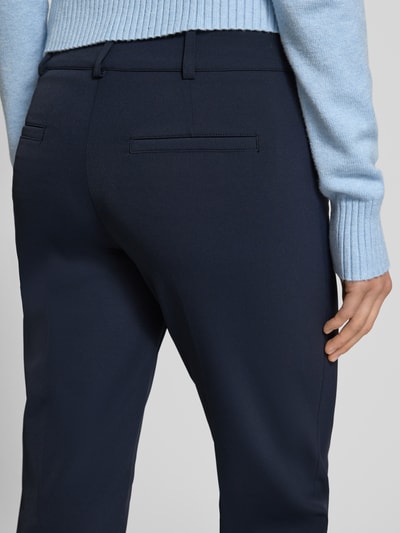 Vrouwenmodel draagt donkerblauwe stoffen broek van Cambio, model 'RENIRA', materiaalmix met stretch, paspelzakken achter, verkort, detailopname.