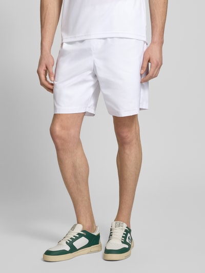 Męski model nosi Relaxed Fit Sport-Shorts mit Logo-Stitching od Lacoste Sport, białe, gładkie, z elastycznym pasem i bocznymi kieszeniami, krój relaxed fit, całkowity widok z przodu.