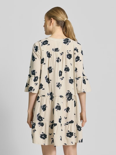 Frauenmodel trägt ausgestelltes Blusenkleid aus reiner Baumwolle Modell 'DICTHE' von Vero Moda mit Allover-Muster und Trompetenärmeln, Ganzkörperansicht Rückansicht.