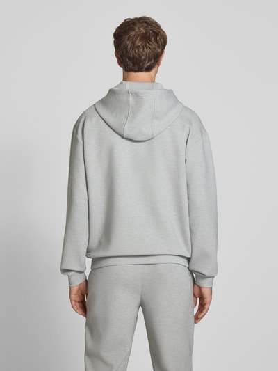 Männermodel trägt Hoodie mit Logo von PUMA PERFORMANCE in Hellgrau, Material-Mix mit Lyocell, Rückenansicht, Ganzkörperansicht Rückansicht.