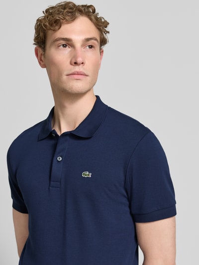 Männermodel trägt Regular Fit Poloshirt aus reiner Baumwolle von Lacoste, Optik: Unifarben, Logo-Detail, Nahaufnahme Oberkörper.