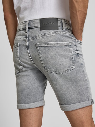 Männermodel trägt Regular Fit Jeansshorts aus Baumwoll-Mix Modell 'PLY MGD 8774' von Only & Sons in hellem Denim mit Label Patch, 5-Pocket-Design, Twillstruktur, Ganzkörperansicht Rückansicht.