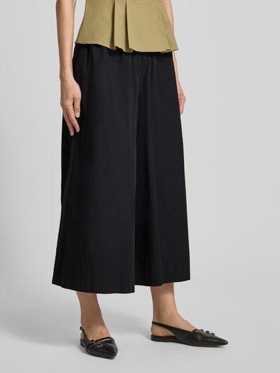 Frauenmodel trägt Wide Fit Stoffhose mit elastischem Bund Modell 'Sunna' von My Essential Wardrobe in Falten-Optik, dunkle Farbe, glatte Textur, Bundweite bei Größe 36: 36 cm, Innenbeinlänge bei Größe 36: 58 cm, Nahaufnahme Unterkörper.