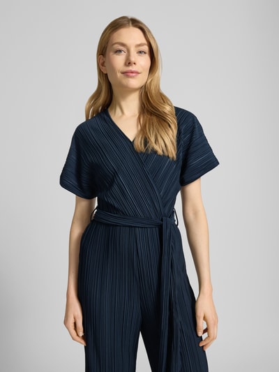 Vrouwenmodel draagt Jumpsuit mit Plisseefalten und Bindegürtel Modell 'Pe44arl' van ZABAIONE in donkerblauw, taillering, V-hals, wikkel-look, gladde textuur, Nahaufnahme bovenlichaam.