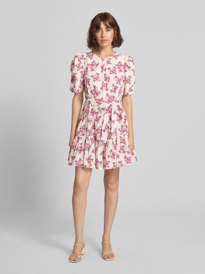 Frauenmodel trägt Minikleid im Allover-Look mit Bindegürtel von Neo Noir aus reiner Baumwolle in A-Linie mit Blumenmuster, Ganzkörperansicht von vorne.