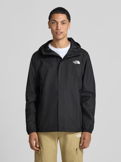 Männermodel trägt schwarze Jacke mit Label-Print Modell 'ANTORA' von The North Face, Reißverschlusstaschen, Ganzkörperansicht von vorne. Herren Jacke, gerade Passform, Kapuze mit Tunnelzug, durchgehender Reißverschluss mit Abdeckleiste, elastische Ärmelabschlüsse, neutrale Farben, glatte Textur.