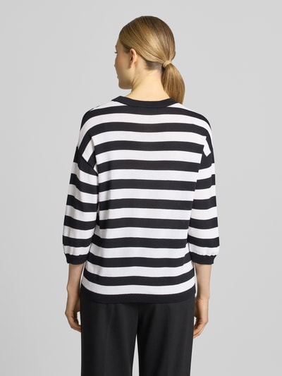 Frauenmodel trägt Regular Fit Oberteil aus Viskose-Mix Modell 'Lani' von GUIDO MARIA KRETSCHMER WOMAN, schwarz-weiße Streifen, Strick-Optik, 3/4-Arm, elastische Ärmelabschlüsse, Rückenlänge 58 cm, Ganzkörperansicht Rückansicht.