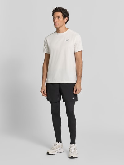 Męski model nosi Tights mit elastischem Bund und Logo od ASICS, czarne, gładka tekstura, dopasowany krój, elastyczny pas, widoczne logo, materiał z dodatkiem stretchu, długość wewnętrzna nogawki w rozmiarze M: 74 cm, pełny widok z przodu.