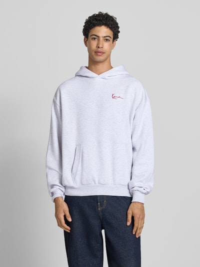 Männermodel trägt Oversized Fit Hoodie mit Logo-Stitching von KARL KANI in hellem Grau, Baumwoll-Mix mit Kapuze und Känguru-Tasche, Vorderansicht, Ganzkörperansicht von vorne.