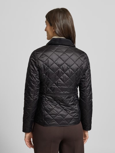 Kobiece model prezentuje kurtkę pikowaną z sztruksowym kołnierzem model 'Deveron' od Barbour, czarna, taliowany krój, nakładane kieszenie, logo haft, długość tyłu 60 cm, szerokość ramion 38 cm, długość rękawów 63 cm, widok całej sylwetki od tyłu.