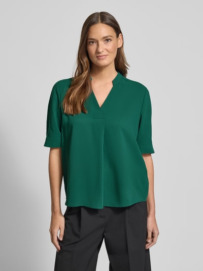 Modelka kobieca nosi Regular Fit Bluse mit V-Ausschnitt von Marc Cain, zielony kolor, stójka, damska bluzka, krój regular fit, długość pleców 59 cm, długość rękawa 29 cm, widok całej sylwetki z przodu.