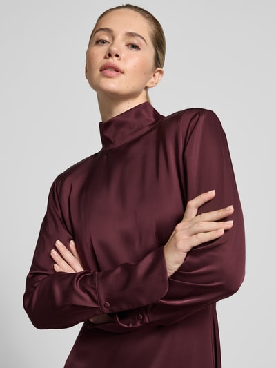 Vrouwenmodel draagt Fließendes Kleid in Maxilänge - curated by Isabelle Hartmann van Style Icon Collection, wijnrode satijnen stof, taillering, lange mouwen, staande kraag, Nahaufnahme bovenlichaam.