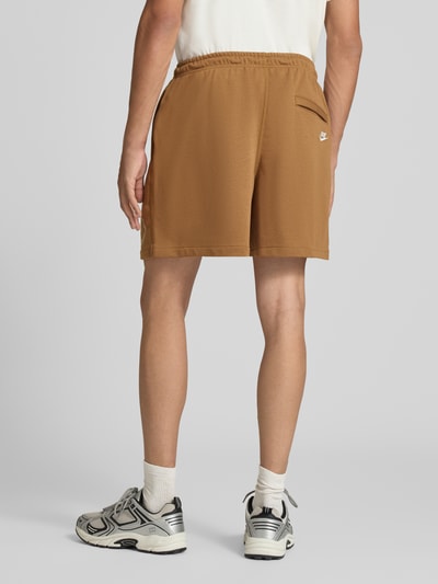 Männermodel trägt Regular Fit Sweatshorts aus Baumwoll-Mix von Nike in Braun, lockere Passform, glatte Textur, Ganzkörperansicht Rückansicht. Herren Sweatshorts von Nike