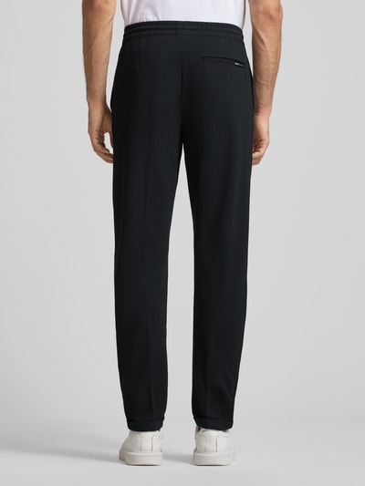 Männermodel trägt Tapered Chino mit Viskose-Anteil von Tom Tailor Denim, Optik: Unifarben, Passform: Tapered, Longline, Ganzkörperansicht Rückansicht.