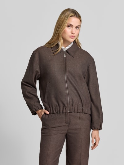 Frauenmodel trägt Regular Fit Blazer mit Reißverschluss von MORE & MORE, braune Farbe, glatte Textur, Eingrifftaschen, Umlegekragen, Ganzkörperansicht von vorne.