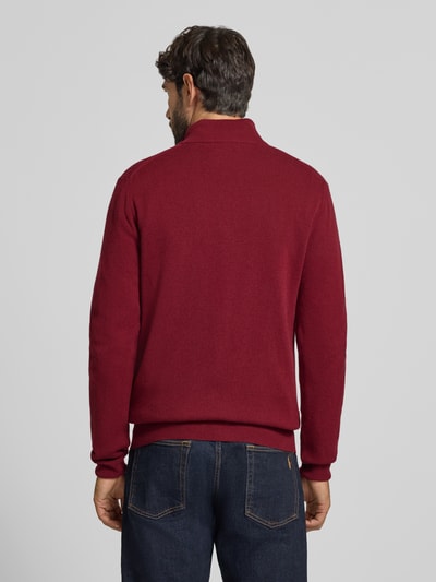 Männermodel trägt Pullover aus reiner Wolle von GANT in dunklem Rot, Feinstrick, Troyerkragen, Langarm, Ganzkörperansicht Rückansicht.