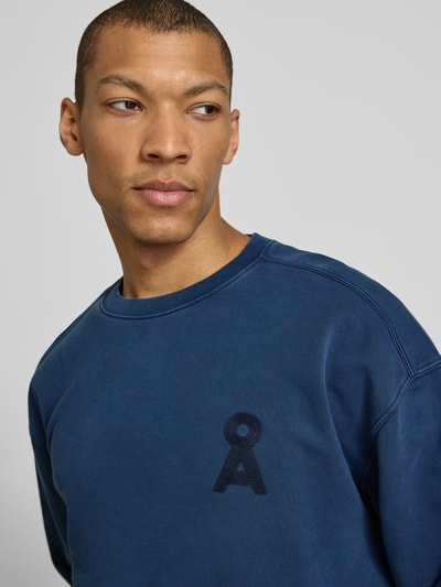 Mężczyzna nosi Relaxed Fit Sweatshirt aus reiner Bio-Baumwolle Modell 'ICONIC Å GMT' od Armedangels, gładki, niebieski, logo-stitching, długi rękaw, okrągły dekolt, materiał typu sweat z czystej bawełny organicznej, zbliżenie na górną część ciała