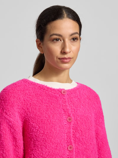Frauenmodel trägt Strickjacke mit Knopfleiste Modell 'ZOLLY' von American Vintage in Pink, grobe Textur, Nahaufnahme Oberkörper.