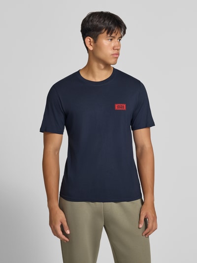 Männermodel trägt Regular Fit T-Shirt aus reiner Baumwolle mit Label-Detail von JACK & JONES in Dunkelblau, Ganzkörperansicht von vorne. Rückenlänge bei Größe M 67 cm, Rundhalsausschnitt.