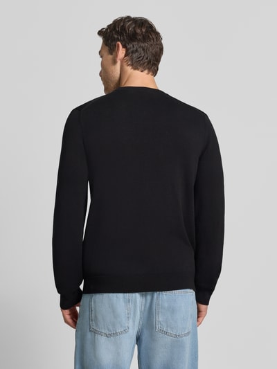 Männermodel trägt schwarzen Regular Fit Pullover aus Baumwoll-Mix von Lacoste, kombiniert mit hellblauer Jeans, Ganzkörperansicht Rückansicht. Herren Pullover von Lacoste.