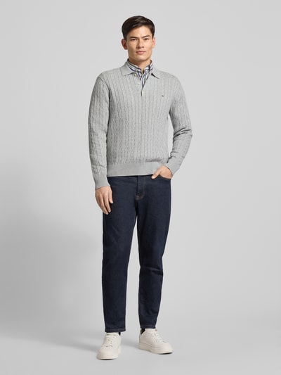 Männermodel trägt Regular Fit Strickpullover aus reiner Baumwolle von Tommy Hilfiger, grau, Zopfmuster, Polokragen, Ganzkörperansicht von vorne
