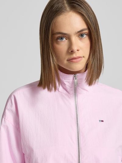 Frauenmodel trägt Relaxed Fit Blouson mit Taillenbändern von Tommy Jeans in Rosa, Stehkragen, Logo-Stitching, Nahaufnahme Oberkörper.