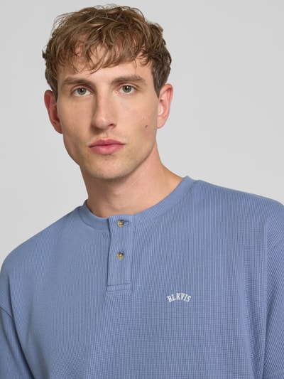 Mężczyznamodel nosi Henley-Shirt mit Strukturmuster und Label-Stitching von BLKVIS, bawełna, krój regular fit, okrągły dekolt, listwa guzikowa, kolor niebieski, fakturowany wzór, wyhaftowane logo, długość tyłu w rozmiarze M: 72 cm, zbliżenie na górną część torsu