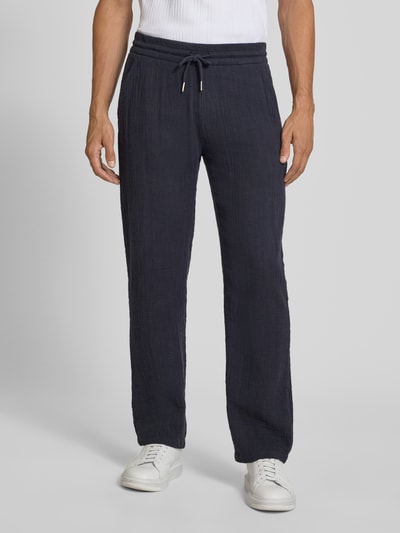 Mężczyznamodel nosi Straight Fit Sweatpants in Musselin-Optik od Lindbergh, ciemnogranatowe, bawełna, muślin, elastyczny pas z tunelem, szerokość w rozmiarze M: 41 cm, długość wewnętrzna nogawki: 81 cm, spodnie z prostymi nogawkami, Ganzkörperansicht von vorne.