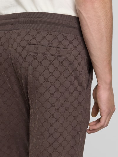 Männermodel trägt braune Herren Sweathose von JOOP! mit Regular Fit T-Shirt aus Baumwoll-Mix Modell 'Korvian', Detailaufnahme Rückansicht.