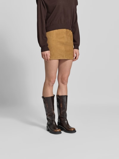 Frauenmodel trägt Minirock aus echtem Ziegenvelours von ROTATE in Beige, Regular Fit, elastischer Bund, Falten-Optik, Ganzkörperansicht von vorne.