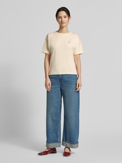 Frauenmodel trägt OPUS T-Shirt mit Stitching Modell 'Salentine' aus reiner Baumwolle in Beige, kombiniert mit blauer Jeans, Rundhalsausschnitt, Regular Fit, Ganzkörperansicht von vorne.