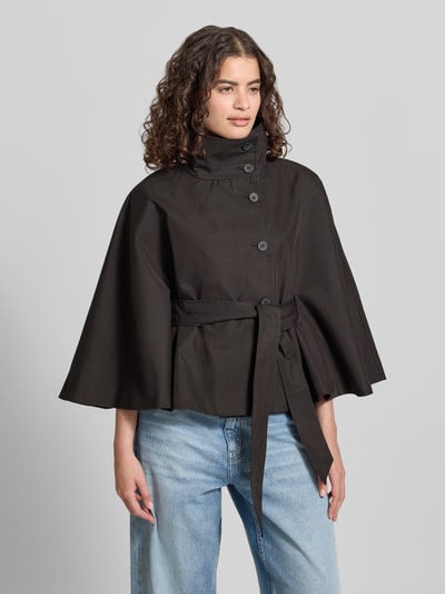 Vrouwenmodel draagt Trenchjacke met Stehkragen Modell 'Isa' van Gina Tricot uit katoenmix, getailleerd model, knoopsluiting, kimonomouwen, strikceintuur. Ganzkörperansicht van voren.