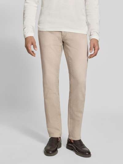 Männermodel trägt Slim Fit Jeans aus Baumwoll-Mix Modell 'Chuck' von Brax in Beige, glatte Textur mit klaren Nähten, Ganzkörperansicht von vorne, Herren Slim Fit Jeans von Brax.