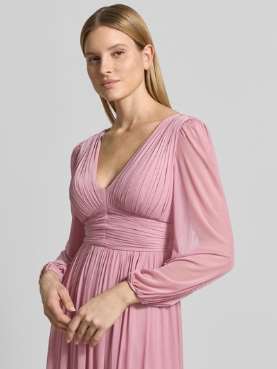 Vrouwenmodel draagt Regular Fit avondjurk in plooien-look van Lipsy, elastische materiaalmix, V-hals, met lange mouwen, getailleerde pasvorm, onderrok, detailaufnahme bovenlichaam.