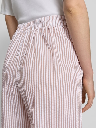 Kobieta nosi spodnie Wide Leg Hose mit elastischem Bund von Apricot z bawełny, wzór na całej powierzchni, długość wewnętrzna nogawki 73 cm, szerokość w rozmiarze S 37 cm, zbliżenie na biodra, widok z tyłu.