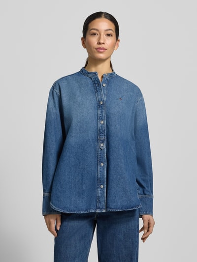 Vrouwenmodel draagt Relaxed Fit Jeansblouse uit katoen-lyocell-mix van Tommy Hilfiger in denimlook met gestikt logo, doorlopende knoopsluiting, lange mouwen met manchet, afgeronde rompzoom, maokraag. Volledige lichaamsaanzicht van voren.