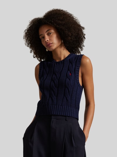 Modelka nosi Bezrękawnik z wyhaftowanym logo od Polo Ralph Lauren z bawełny, krój regular fit, prążkowane wykończenia, okrągły dekolt, długość tyłu w rozmiarze S 48 cm, ciemnogranatowy, duże sploty, całkowite ujęcie od przodu.
