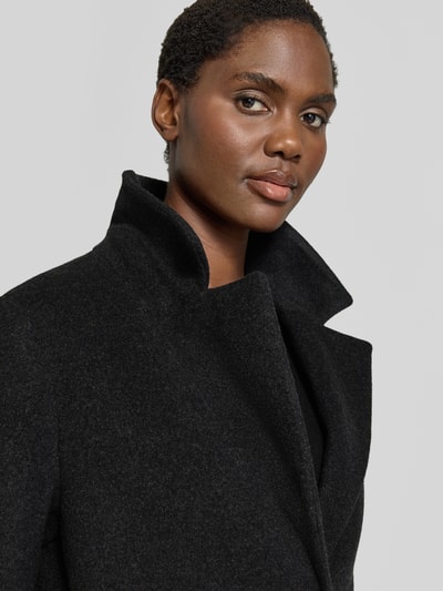 Frauenmodel trägt Mantel aus Schurwolle-Mix mit Kapuze von CINQUE, klassisches Revers, schwarzer Stoff, strukturierte Oberfläche, Nahaufnahme Oberkörper. Das Modell zeigt einen Damen Mantel mit Kaschmir-Anteil, Straight Fit, Reißverschluss und Knopfleiste, seitlichen Eingrifftaschen. Rücklänge bei Größe 36: 109 cm, Schulterbreite 38 cm, Brustweite 50 cm, Ärmellänge 63 cm.