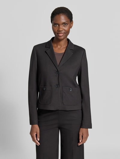 Frauenmodel trägt Blazer aus Viskose-Mix mit Reverskragen von MORE & MORE, tailliert, schwarz, mit aufgesetzten Taschen, Ganzkörperansicht von vorne.